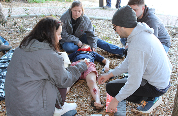 Several individuals gathered around patient providing care in nature setting.