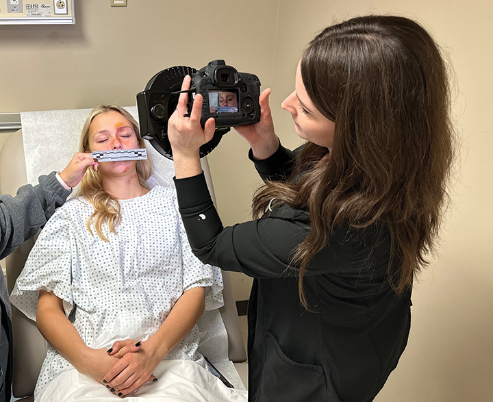 Nurse using camera to collect evidence from person in hospital bed.
